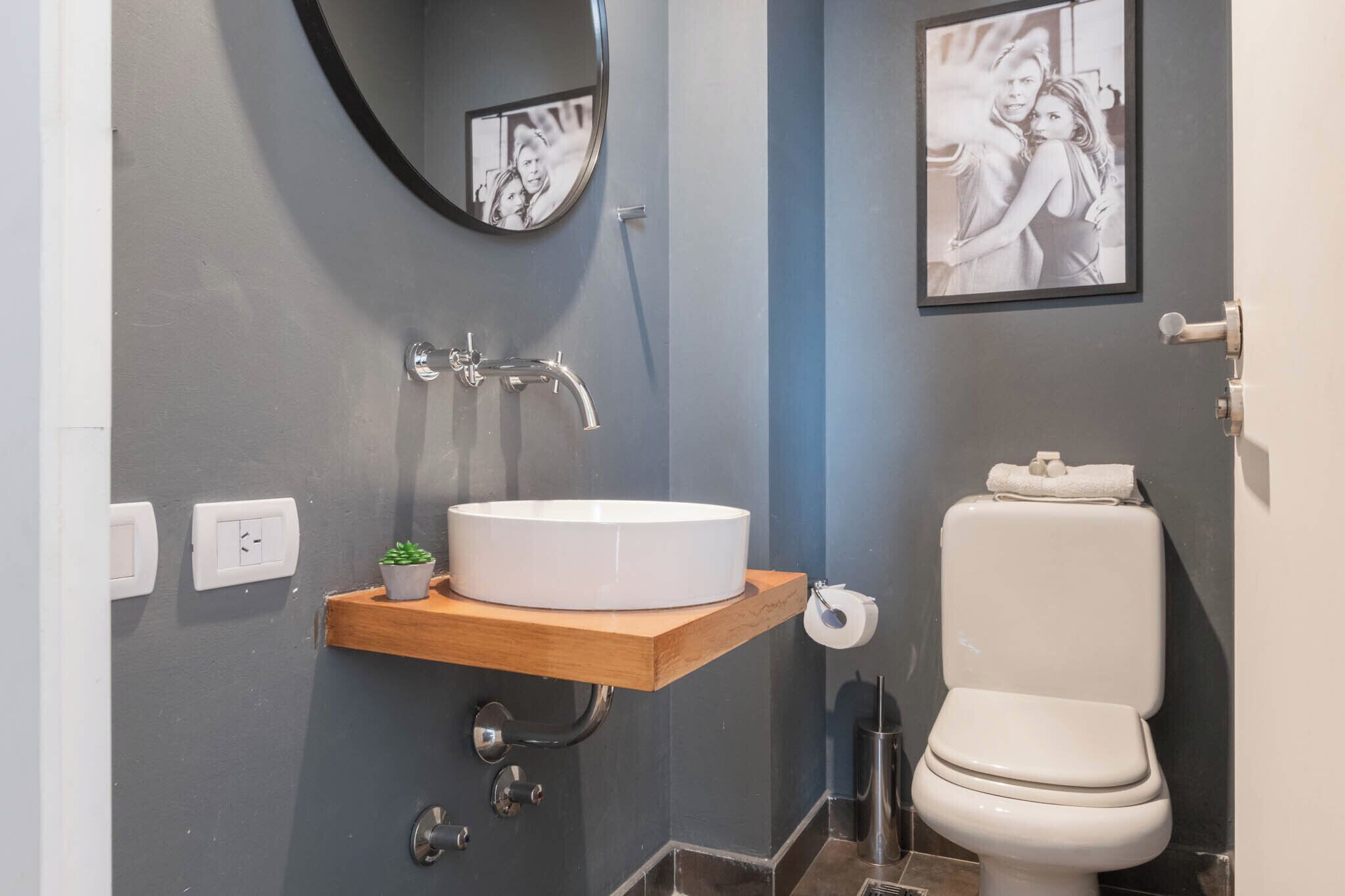 A bathroom with a white sink, a mirror, a toilet, and a framed photo on the wall.