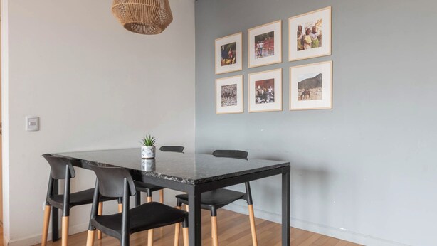 A dining area with a black table, four chairs, and framed pictures on the wall. - MOT Concepcion Arenal (Buenos Aires)