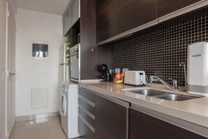 Una cocina moderna con lavadora, cafetera, tostadora y pileta.