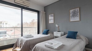 A bedroom with two beds, a window, a nightstand, and a framed map on the wall. - MOT Concepcion Arenal (Buenos Aires)