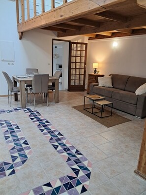 Una sala de estar con una mesa de comedor, sofá y alfombra estampada.