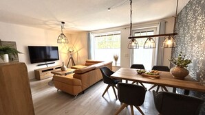 Un salon moderne comprenant un canapé, une table à manger, des chaises et un téléviseur.