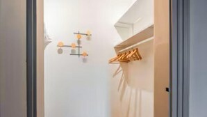 Um corredor com um porta-roupas e um candeeiro na parede.