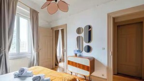 Quarto com cama, penteadeira e janela com cortinas.
