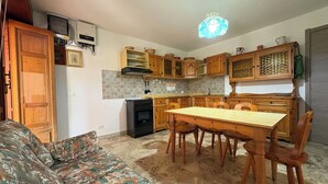Una cocina compacta con armarios de madera, una mesa de comedor y un sofá.