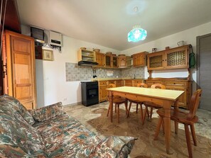 Eine kleine Küche mit Holzschränken, einem Esstisch und einer Couch.