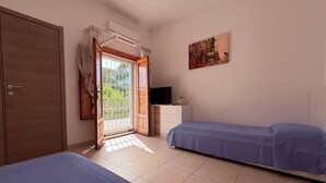 Un dormitorio con dos camas, televisión, armario y ventana con cortinas.