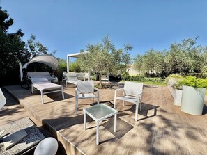Eine Gartenlaube mit Sitzgelegenheit, einer Pergola und Blick auf den Garten.