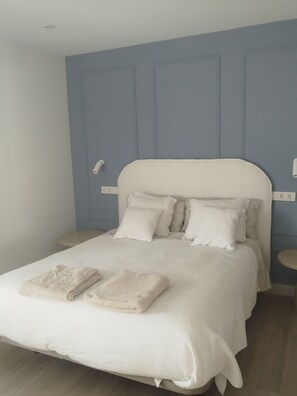 Ein Schlafzimmer mit Bett, Kissen, Nachttisch und Steckdose.