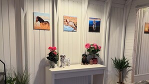 Une pièce avec un plafond en bois, un comptoir blanc agrémenté d’objets décoratifs et des tableaux encadrés accrochés au mur.