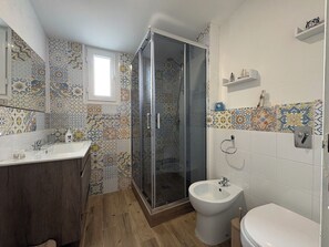 Ein Badezimmer mit Dusche, Bidet und Waschbecken.