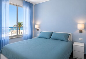 Ein Hotelzimmer mit einem Bett, zwei Nachttischen und Blick auf den Strand.