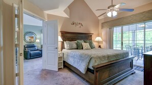 Ein Schlafzimmer mit einem Bett, Nachttischen, einem Deckenventilator und Blick durch ein Fenster.