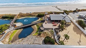 Un complejo turístico frente al mar con playa, un lago pequeño y un muelle.