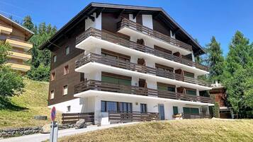 Un immeuble à plusieurs étages doté de balcons, d’un panneau indiquant qu’il est interdit de se garer et d’une zone herbeuse devant.