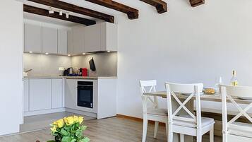 Une cuisine moderne avec des meubles blancs, une table à manger avec des chaises blanches et un plafond en bois.
