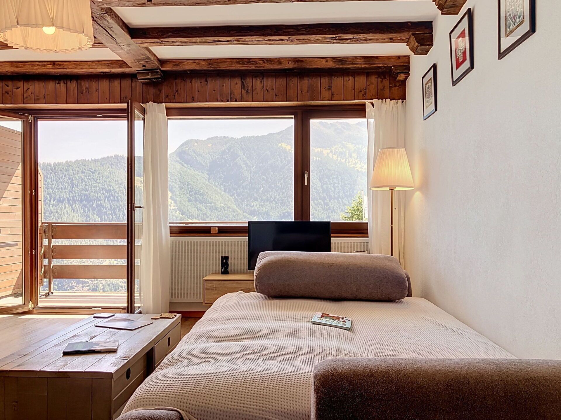 Une chambre à coucher avec un lit, un bureau, une télévision et une fenêtre donnant sur la montagne.