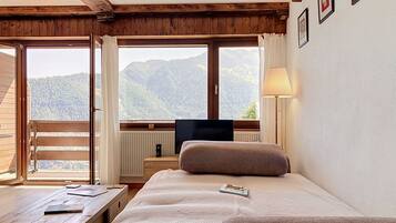 Une chambre à coucher avec un lit, un bureau, une télévision et une fenêtre donnant sur la montagne.