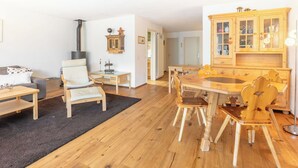 En hyggelig stue med pejs, møbler i træ og et køkkenområde med skabe.