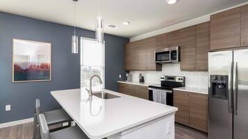 Una cocina moderna con una isla blanca, electrodomésticos de acero inoxidable y armarios de madera.