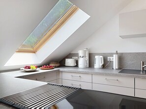 Eine moderne Küche mit Oberlicht, Kaffeemaschine, Wasserkocher und Obstschale.