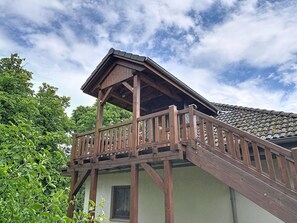 Ein Holzbalkon mit geneigtem Dach, einem Fenster und einem Geländer.