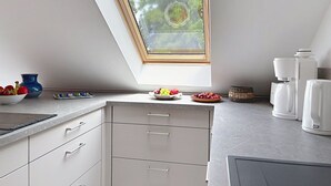 Una cucina moderna con un lucernario, mobili bianchi, una macchina da caffè e una ciotola di frutta.