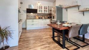 Una cocina moderna con armarios blancos, una mesa de comedor de madera y una lámpara colgante.