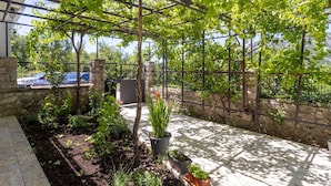Un jardín cubierto con un pérgola, paredes de piedra y plantas en macetas.