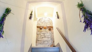 A staircase with a stone wall at the top, leading to a room with white walls and a wooden handrail.