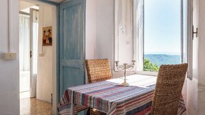 A room with a table set for two, a view of the outdoors, and a door leading to another room.