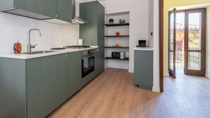 Eine moderne Küche mit Einbauherd, Backofen und Spüle, Holzboden und Blick auf den Außenbalkon.