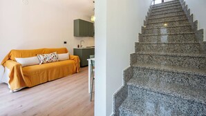 Ein modernes Interieur mit Holzboden, einer Couch, einer Küchenzeile und einer Granittreppe.