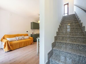 Ein modernes Interieur mit Holzboden, einer Couch, einer Küchenzeile und einer Granittreppe.