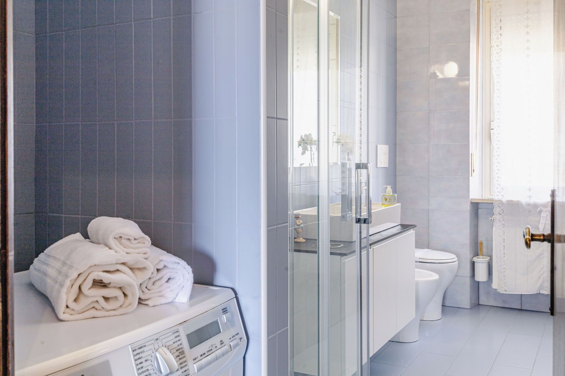A modern bathroom with a glass shower enclosure, a white toilet, and a built-in sink.