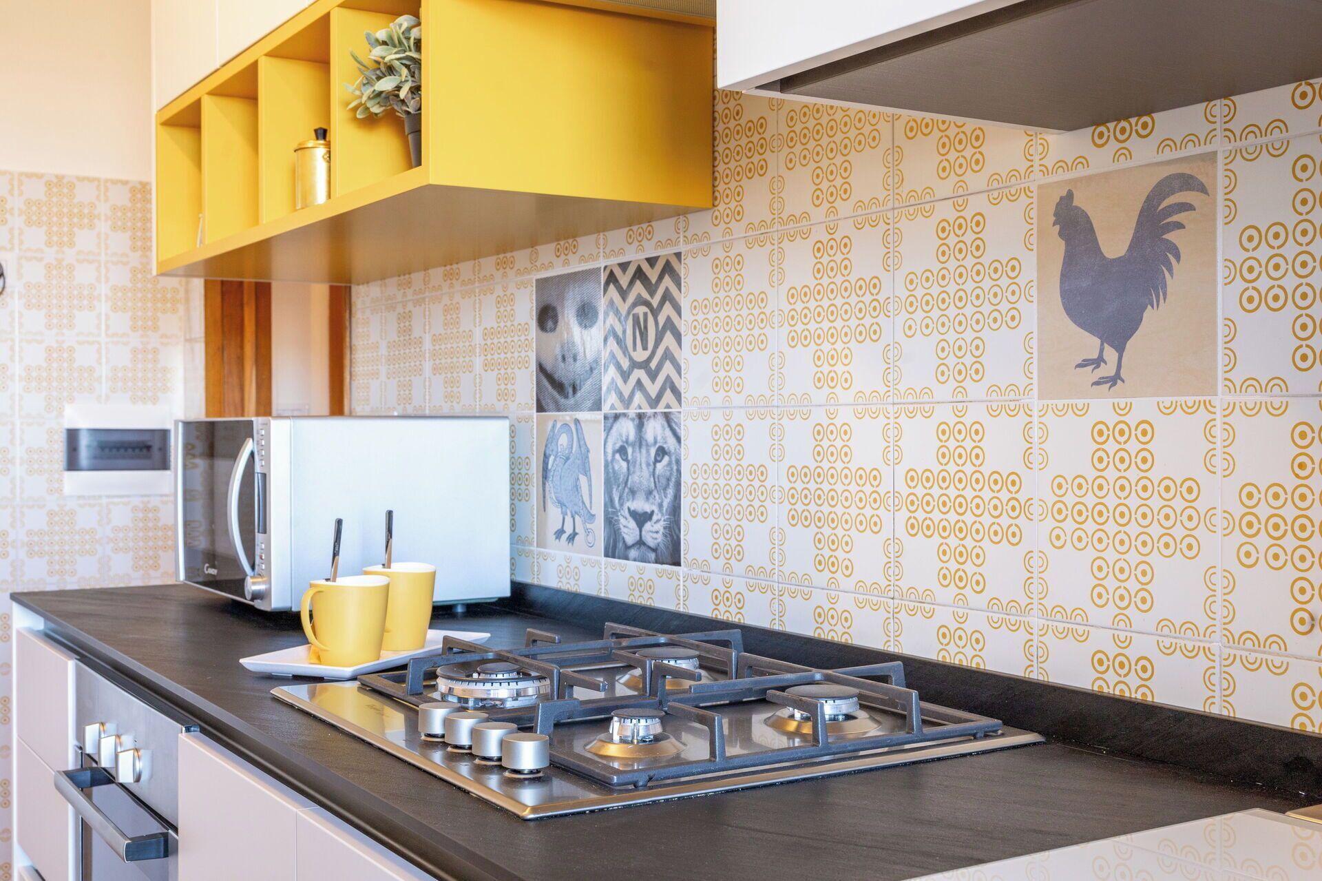 Une cuisine moderne équipée d’une cuisinière à gaz, d’appareils électroménagers en acier inoxydable et de meubles de couleur jaune.