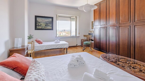 Hotellihuone, jossa on kaksi sänkyä, suuri ikkuna, puupanelointi, taulu ja näkymä kaupunkiin.