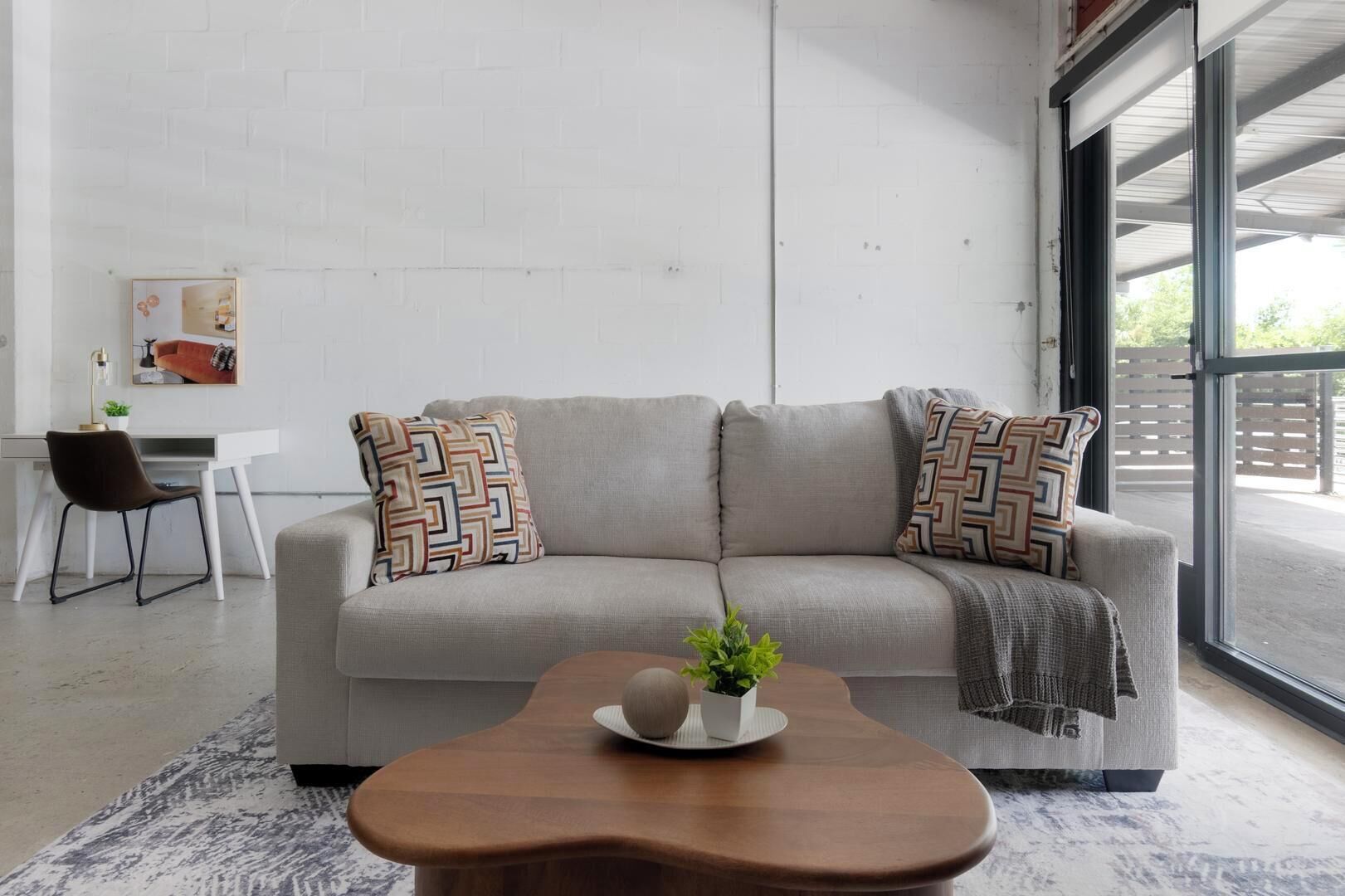 A modern living room with a sofa, a coffee table, and a desk with a chair.