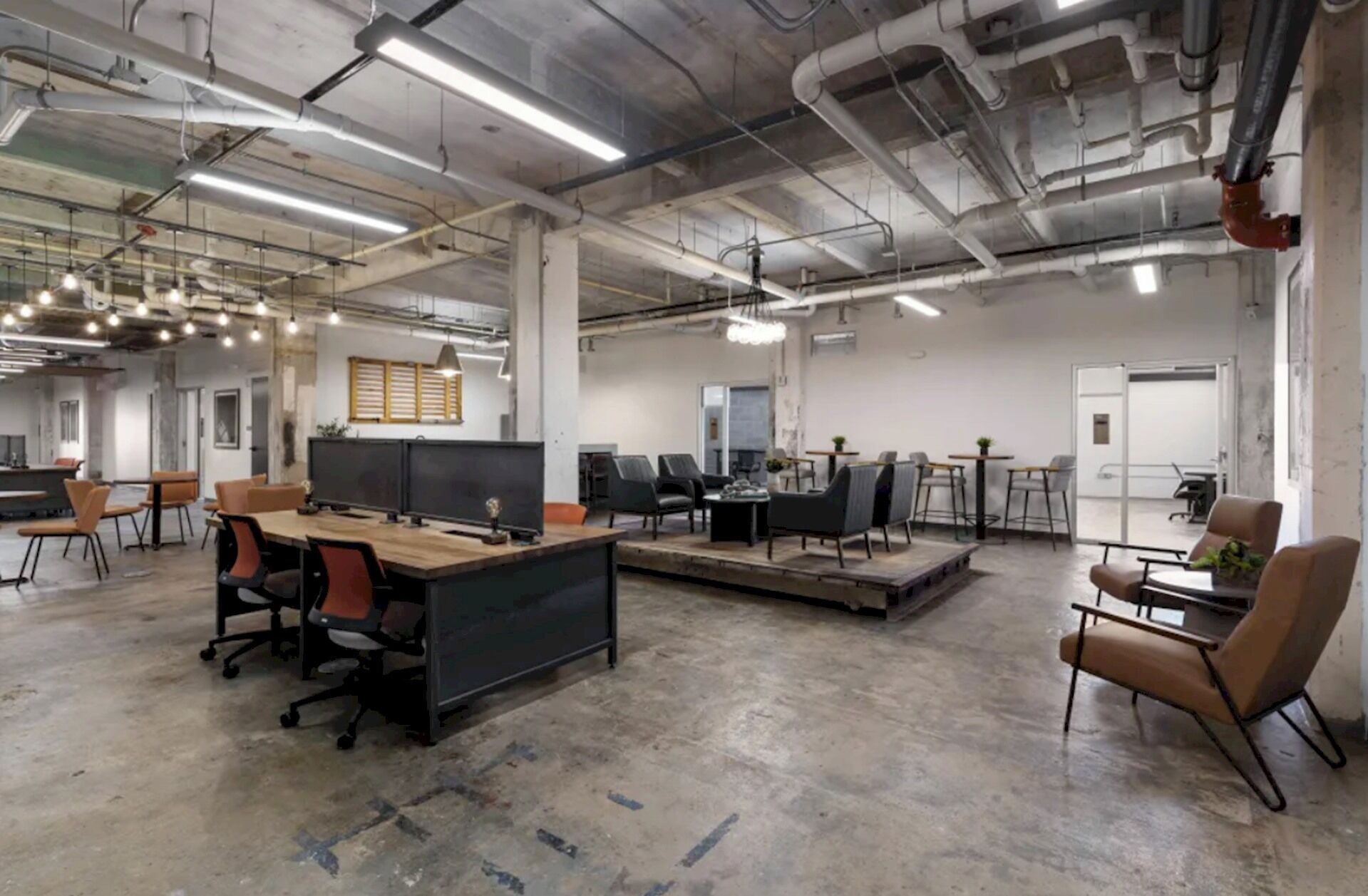 An open-plan office with desks, chairs, and a large table.