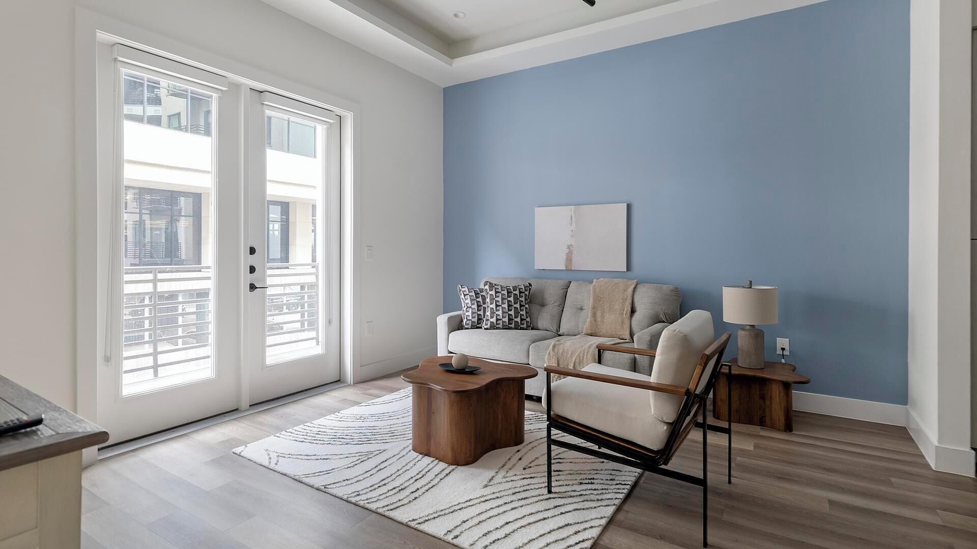 A modern living room with a blue accent wall, a sofa, a coffee table, and a lamp.