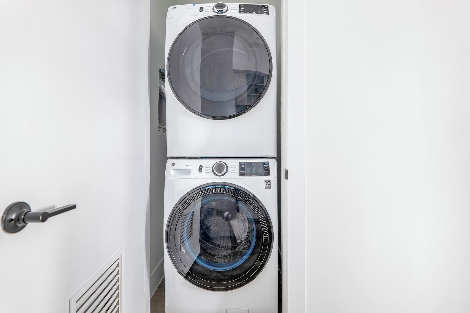 A stacked washer and dryer unit in a room with a door.