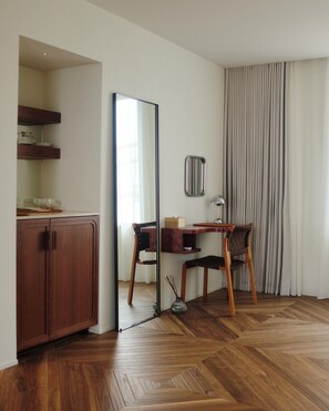 A room with a wooden herringbone floor, a desk with a chair, a mirror, a cabinet, and a window with curtains. - MIZUTANI (Tokyo)