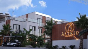 A modern hotel with a prominent sign, a golf cart, and palm trees.