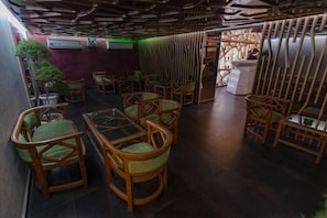 A room with wooden furniture, a glass table, and a green plant. - The India Benares (Varanasi)