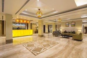 A hotel lobby with a reception desk, seating area, and artwork on the walls. - The India Benares (Varanasi)