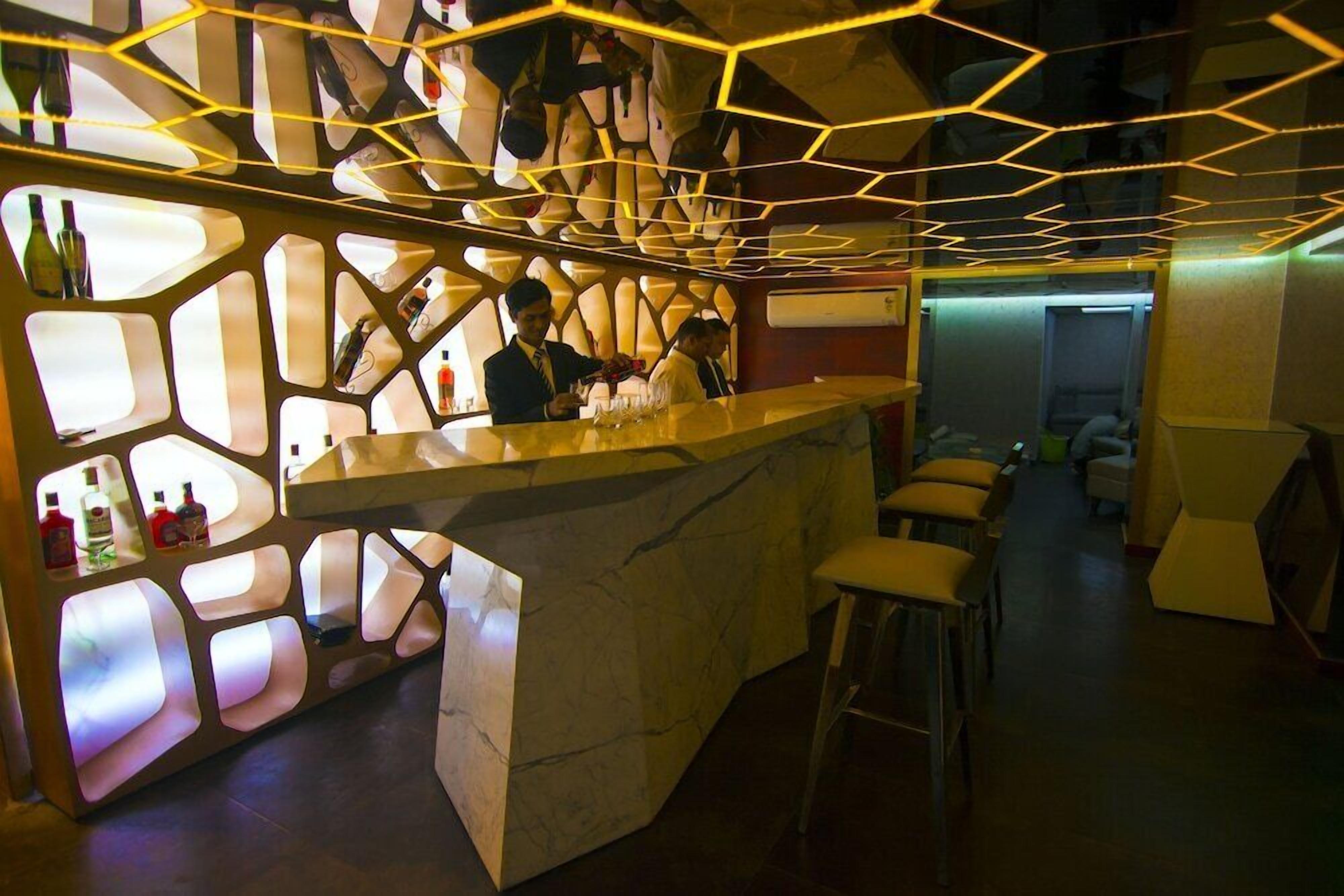 A bar area with a marble counter, stools, and a geometric light fixture.