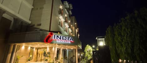 A hotel named 'India Benaras' with a modern facade, a well-lit entrance, and a staircase leading to the lobby.