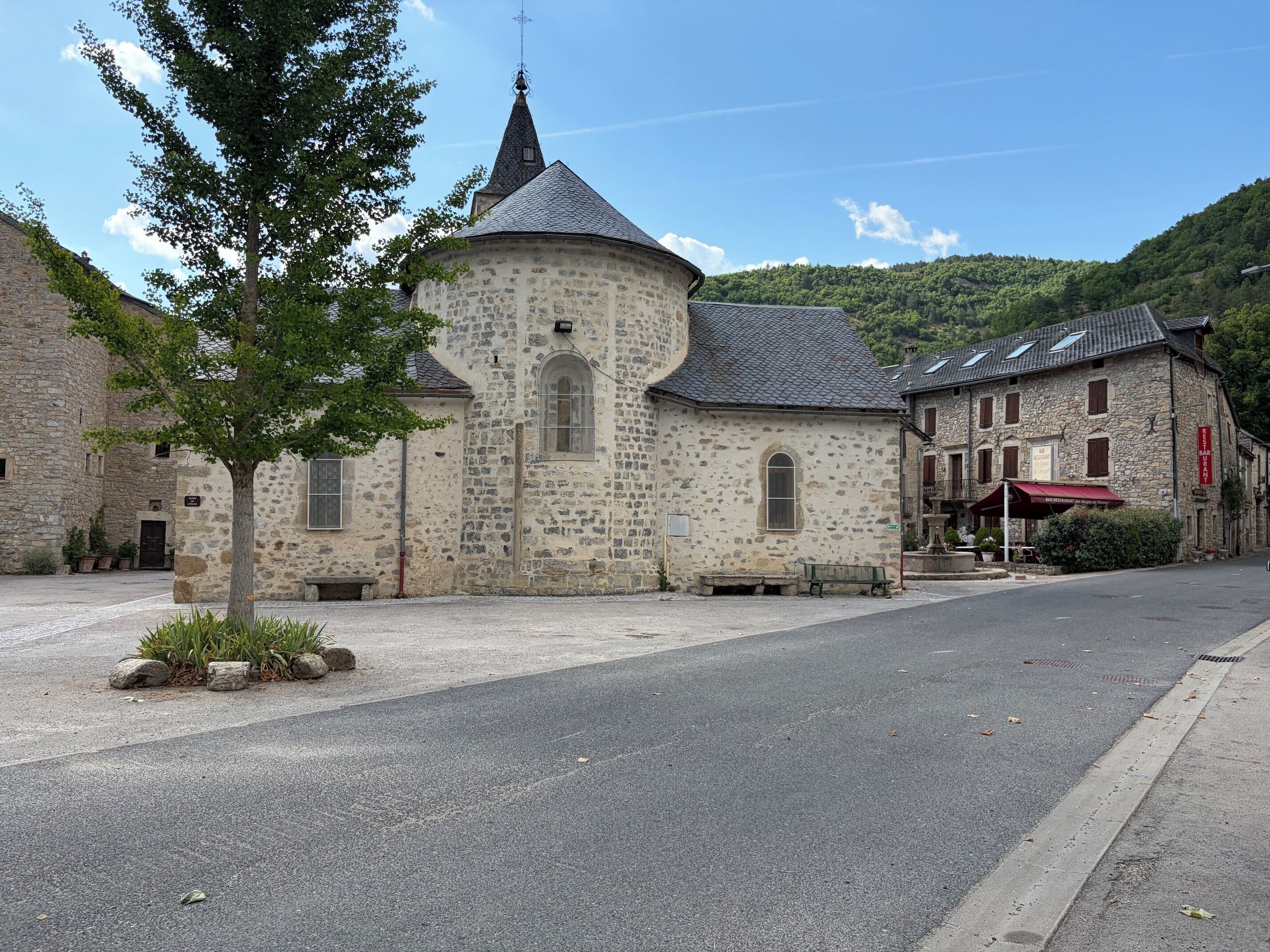 Un edificio de piedra con una torre, una calle empedrada y un banco.