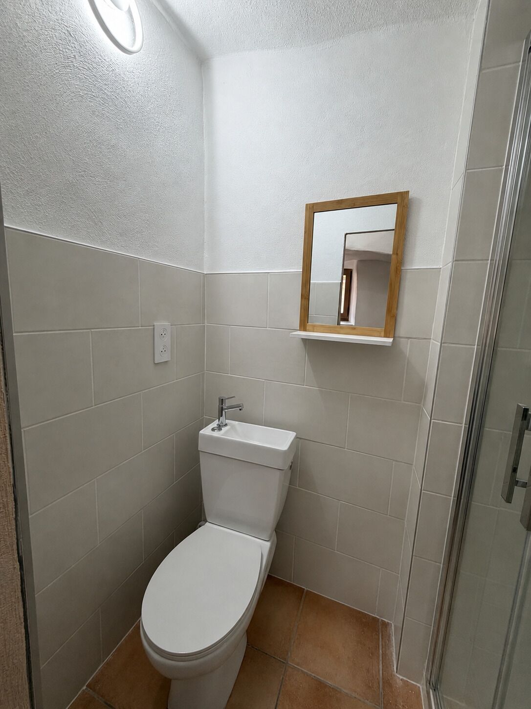 Un baño con inodoro, lavamanos y espejo.