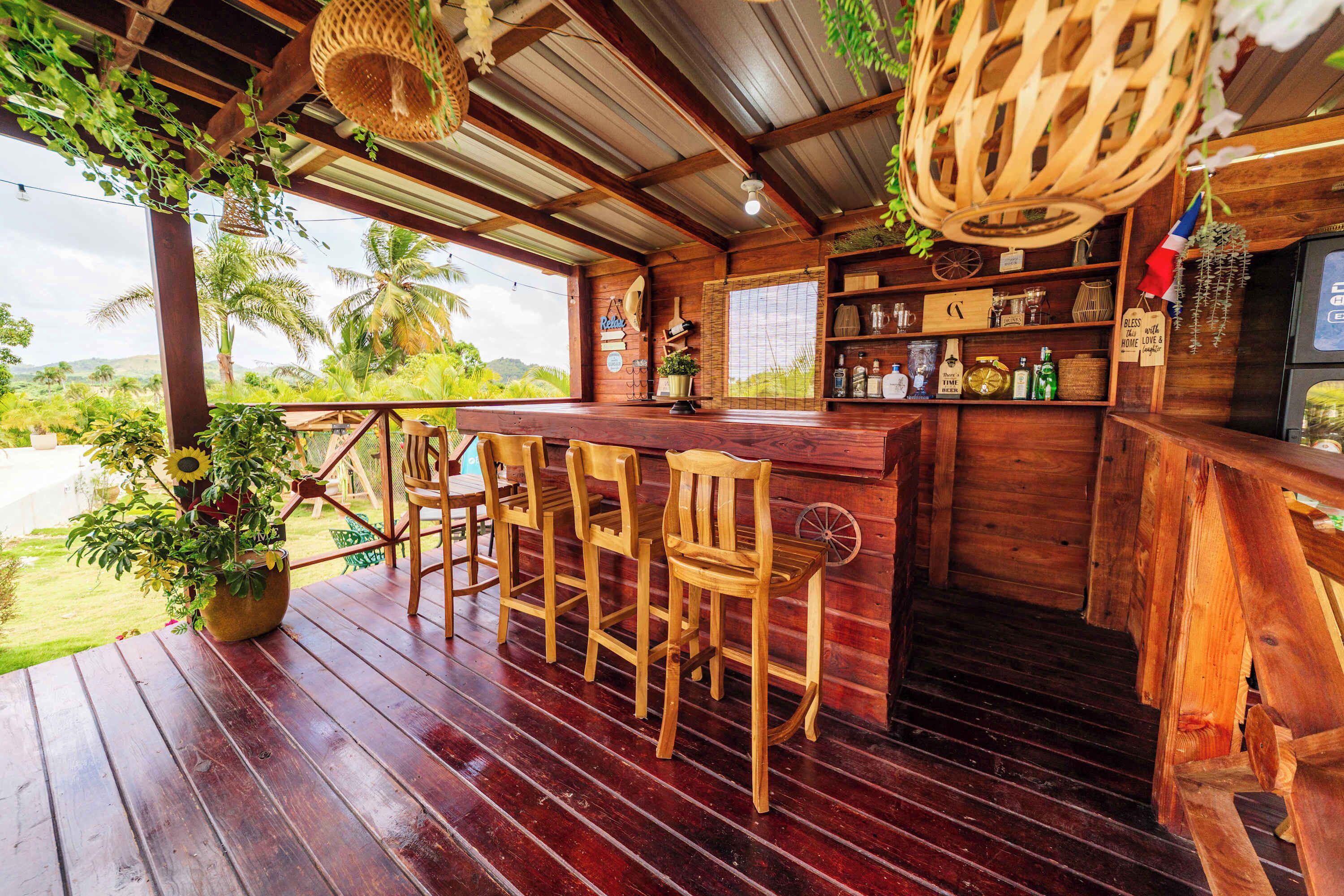 A wooden bar area with chairs, a potted plant, and a view of palm trees.